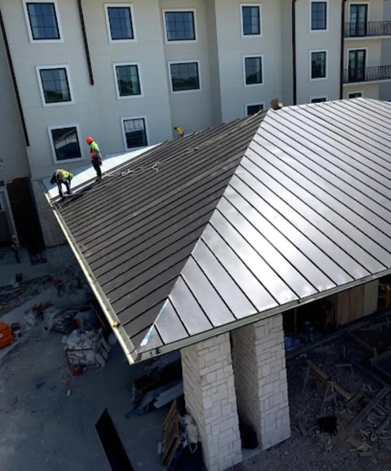 Crew installing standing seam metal roof panels on a commercial project in Poughkeepsie